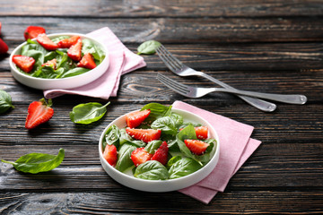 Plates with tasty strawberry spinach salad on table