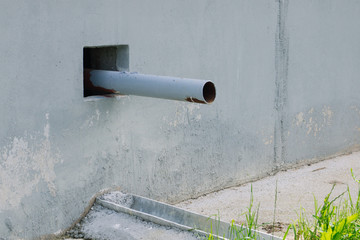 Drainpipe. Gray wall with drain pipe and gutter. Draining the water from the roof. Natural. Water drain or ditch on the road