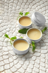 Containers with lemon balm salve and leaves on textured surface