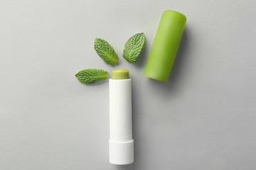 Hygienic lipstick with lemon balm and leaves on light background