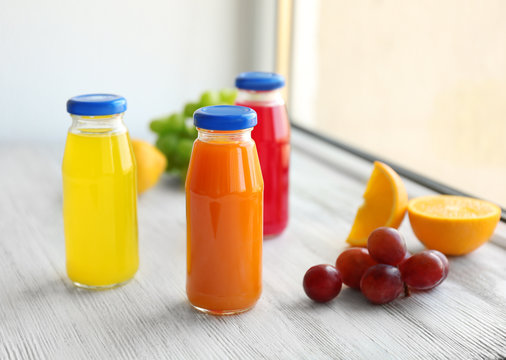 Delicious juices in bottles and fruits on window sill