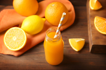 Delicious orange juice in bottle on wooden table