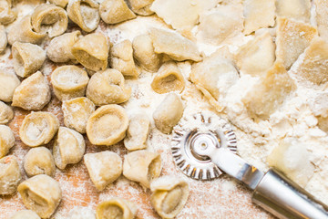 Italian ravioli on a wooden vintage wooden board, sprinkled with flour. Ravioli homemade. Top view.