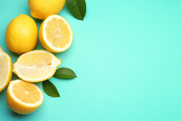 Composition of delicious fresh lemons with green leaves on color background