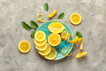 Saucer with delicious sliced citrus fruit and lemon peel on grey background