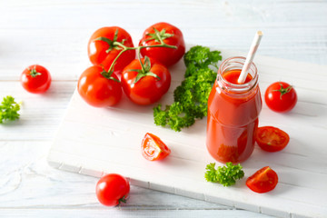 Delicious juice in bottle and tomatoes on wooden board
