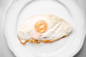 Plate with over hard fried egg on light background