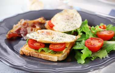 Plate with delicious egg sandwiches, vegetables and beacon on table, closeup