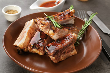 Plate with delicious pork ribs and rosemary on table, closeup