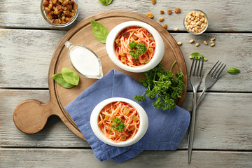 Bowls with delicious carrot raisin salad on wooden board