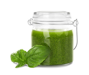 Jar of delicious sauce with basil leaves on white background