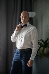 Groom waits for the bride near the window at home