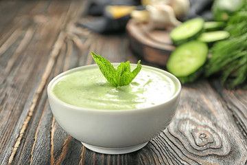 Delicious yogurt sauce in bowl on wooden background