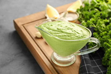 Delicious yogurt sauce in gravy boat with ingredients on grunge background