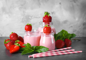 Jars of delicious strawberry homemade smoothie on grey background