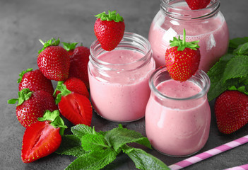 Jars of delicious strawberry homemade smoothie on grey background