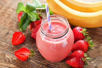 Jar of delicious strawberry and banana homemade smoothie on wooden background