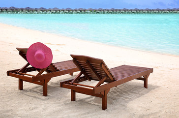 Fototapeta na wymiar Wooden sun loungers on beach at sea resort
