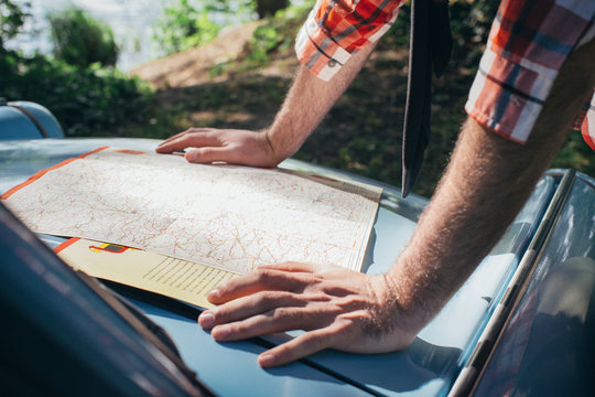 Close Up of Young Man Looking at Road Map on Car Hood