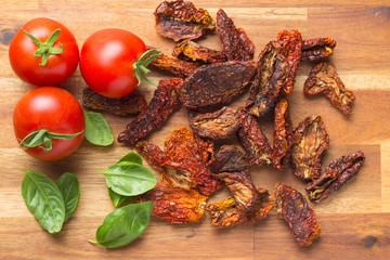 Dried sliced tomatoes and fresh tomatoes with basil leaves.