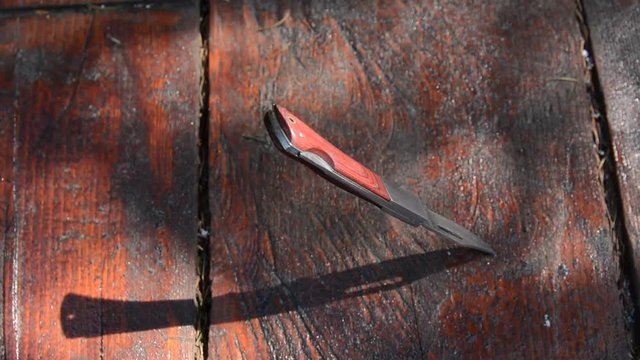 Sharp hunting knife stuck in a wooden table, turning from blurry to focus