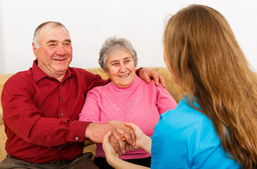 Smiling elderly couple and young caregiver