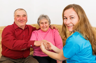 Smiling elderly couple and young caregiver