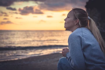 Pensive lonely smiling woman looking with hope into horizon during sunset at beach © splendens