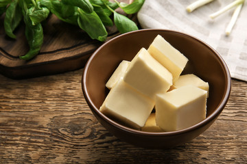 Bowl with cubes of butter on wooden table