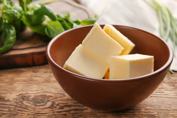 Bowl with cubes of butter on wooden table