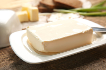 Piece of butter in dish on wooden table