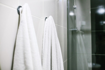 White towels hang on the wall in the bathroom. Cleanliness, shower.