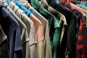 Background: clothing made up of sweatshirts and shirts (autumn / winter) hung on hangers in a...