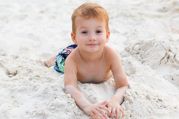 Little boy resting on a sandy beach