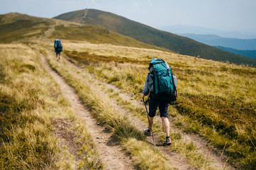 Happy healthy traveler with backpacks reaching top in carpathian mountains. Hiking activity....