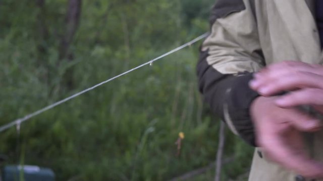 fisherman puts worms as bait for the fish on the hook rod