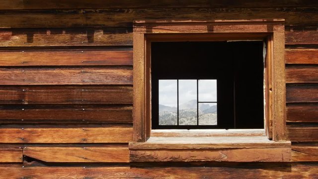 A window peers through a small wooden cabin.