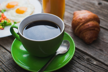 Coffee in a green mug on wooden surface