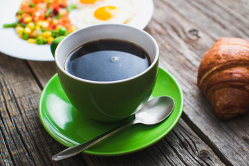Coffee in a green mug on wooden surface