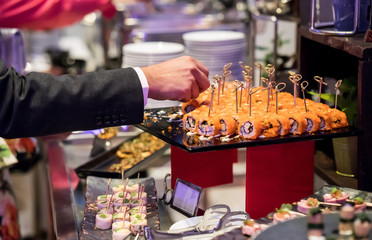 Businessman hands pricking califonia sushi roll in cocktail buffet