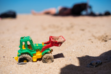 Fototapeta na wymiar Tractor toy on the sandy beach