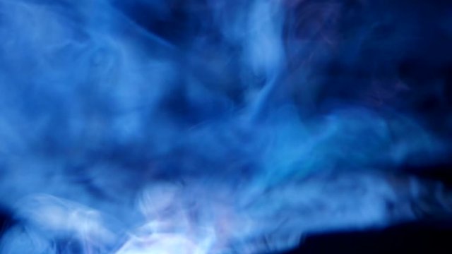 Closeup of blue light rays from projector, spreading through smoke