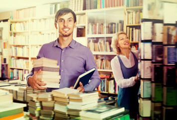 Young smiling man having book pile in hands