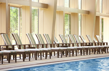 Chaise lounges near swimming pool in luxury hotel
