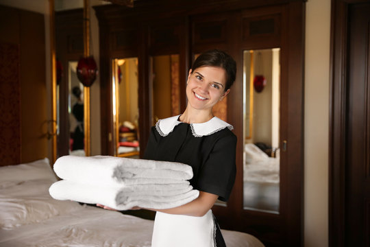 Chambermaid holding clean towels in hotel room