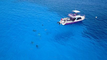 Naklejka premium SCUBA divers and a dive boat in clear, blue, tropical waters viewed from the air