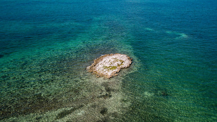 A tiny coral island surrounded by tropical reef viewed from the air