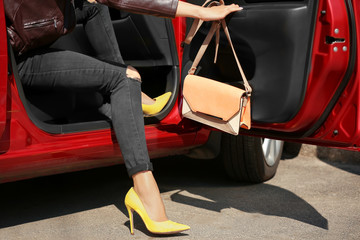 Young woman with slim legs in high heels getting out of car