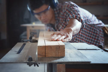 Young carpenter working with circular saw in shop