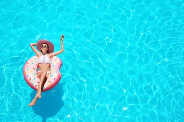 Fototapete Rund Beautiful young woman with inflatable donut in blue swimming pool © Africa Studio
